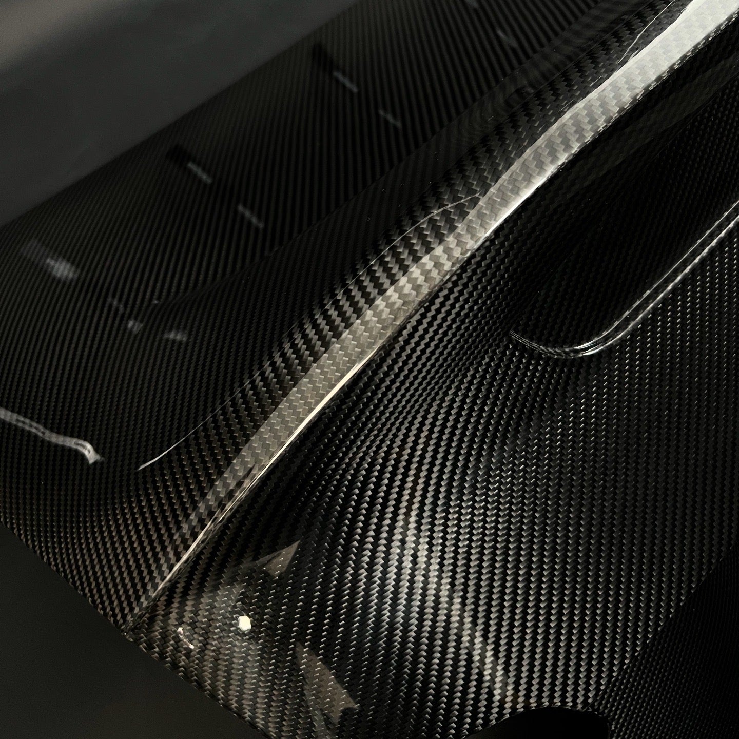 CarbonXtreme dry carbon fiber surface detail, glossy clear coat and weave on a BMW trunk edge