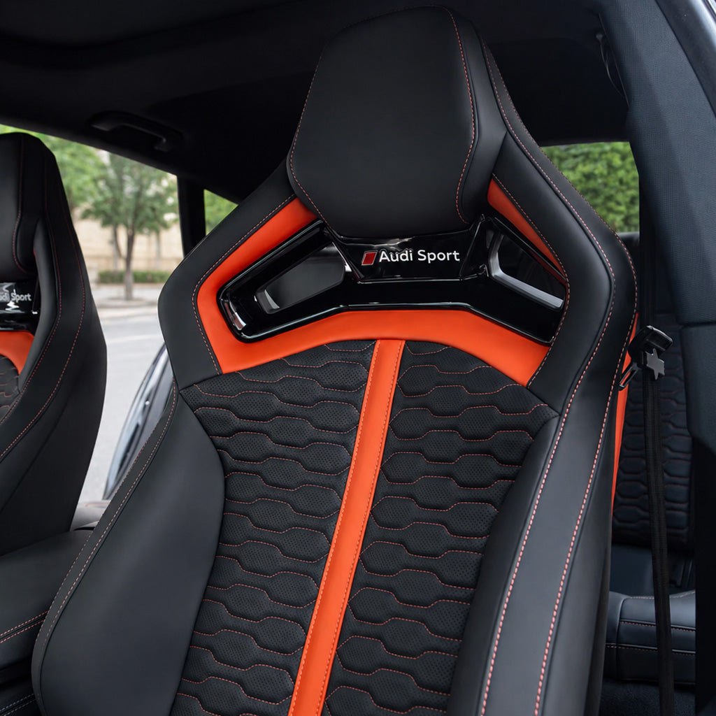 Audi RS Sport Bucket Seat backrest – black leather with orange vertical accent stripes, wave-quilted center and Audi Sport checkered badge on shoulder bridge