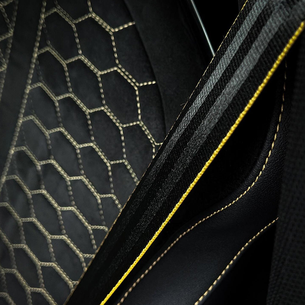 Audi RS bucket seat material detail – dark Alcantara honeycomb bolster meeting black Nappa leather with gold accent stitching edge