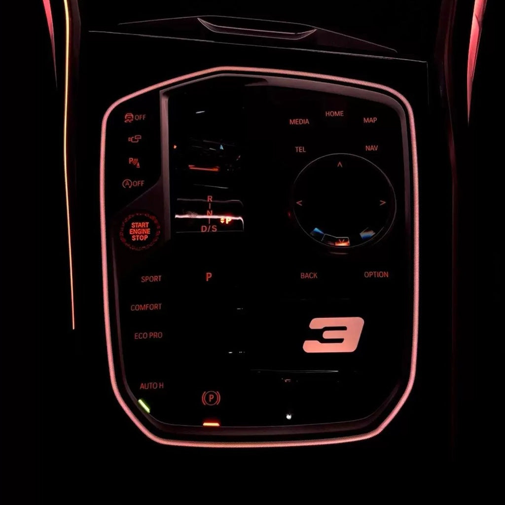 BMW M Illuminated Gear Selector Surround installed – warm pink rose LED glow with illuminated 3 Series badge in BMW G-series cabin