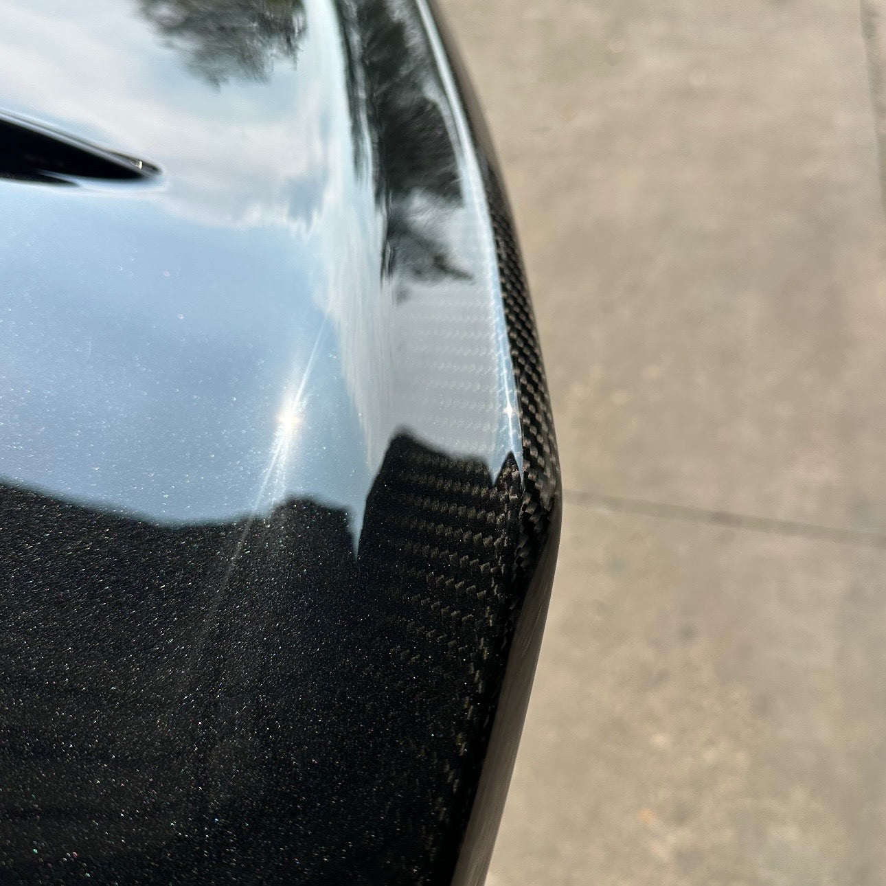 BMW G87 M2 CS carbon fiber trunk lid in gloss black OEM paint with a carbon fade, body color blending into exposed clear coated carbon weave at the ducktail