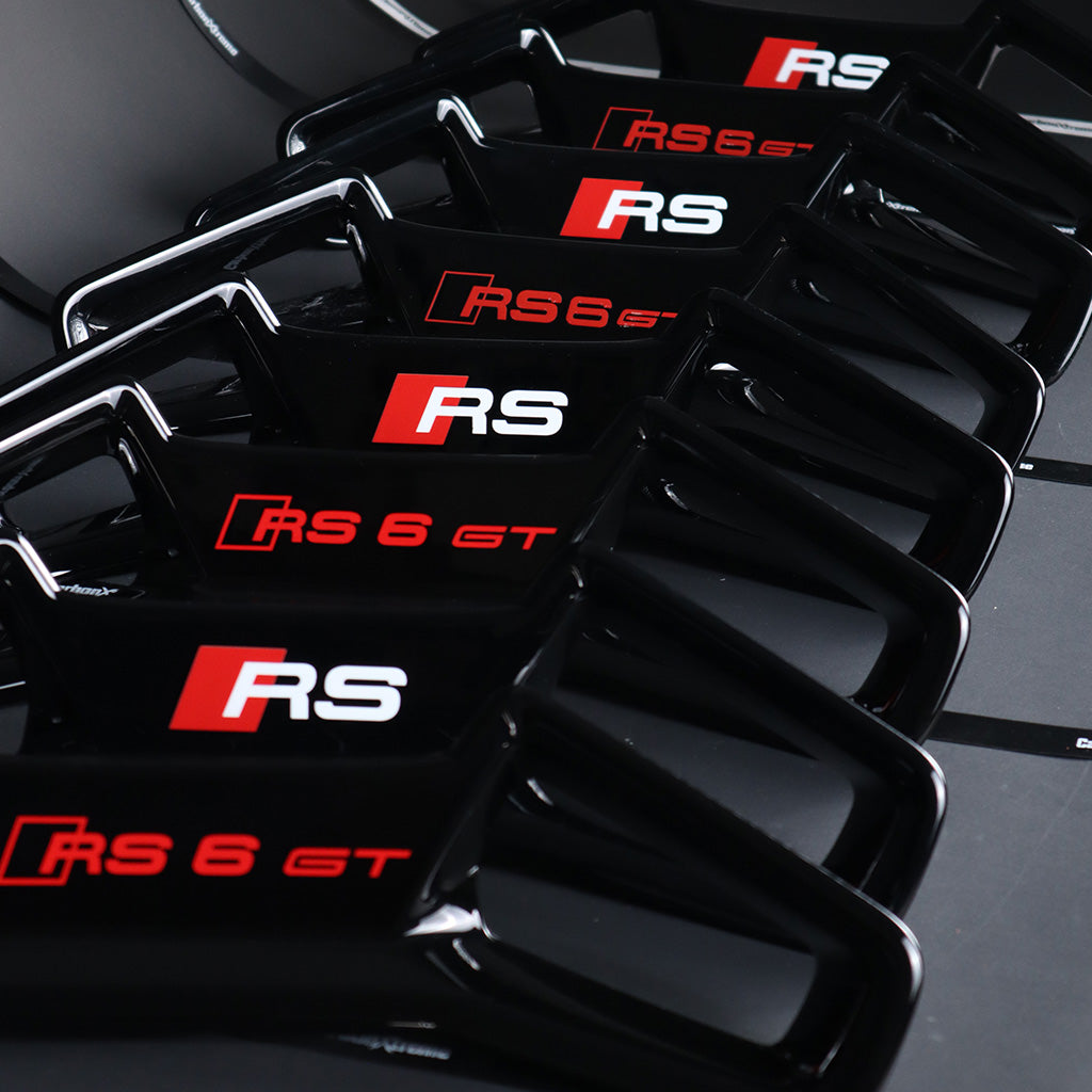 Audi RS seat headrest trim panel lineup – gloss black RS and RS6 GT branded options displayed in fan arrangement
