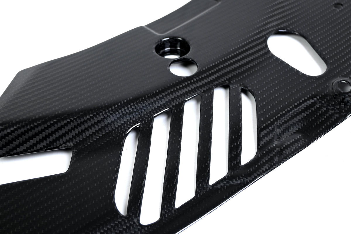 BMW G22 4 Series carbon fiber headlight cover panels are seen close up with tall slots below a recessed hole.