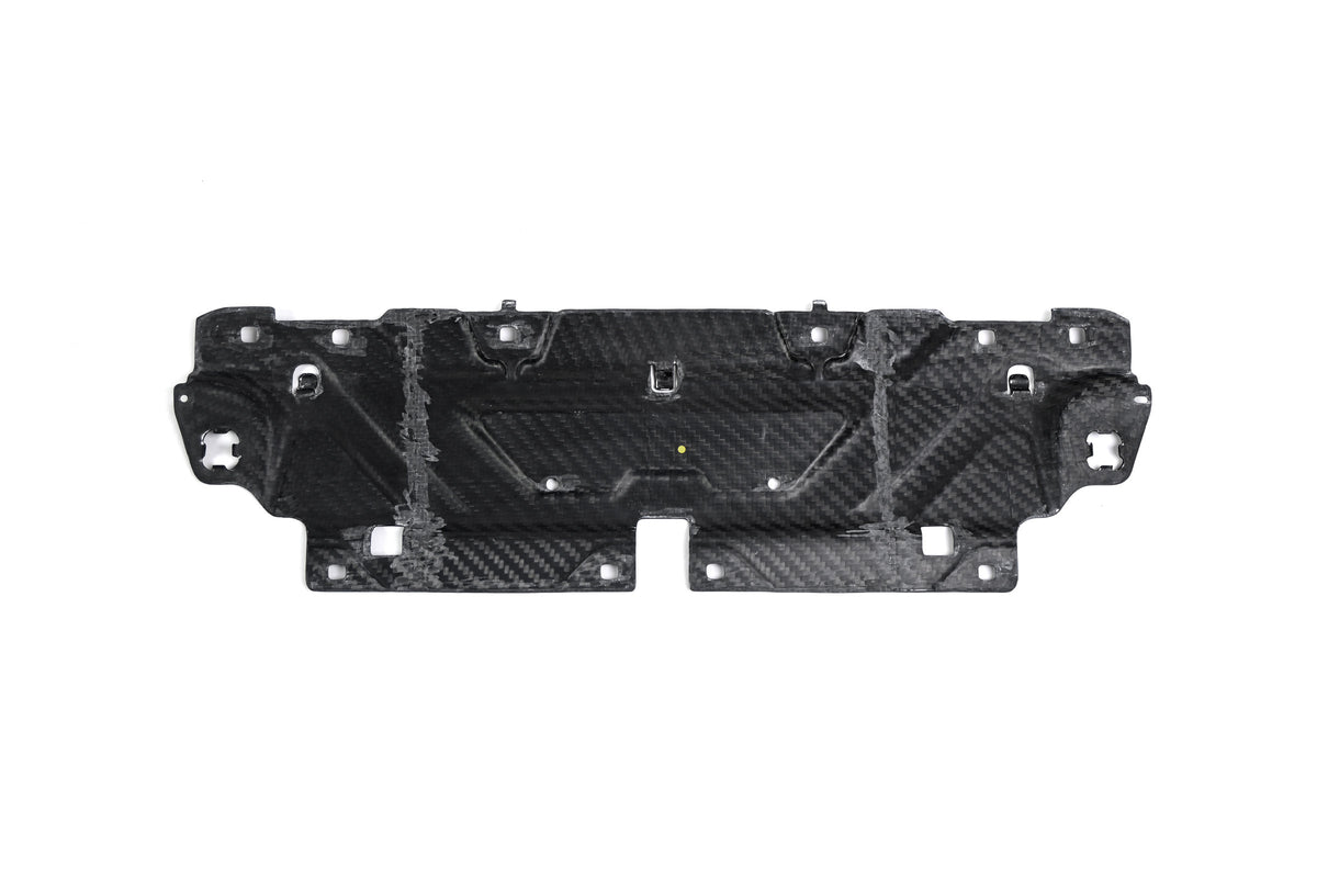 BMW G22 4 Series carbon fiber slam panel cover is shown from the underside with cutouts and mounting tabs.