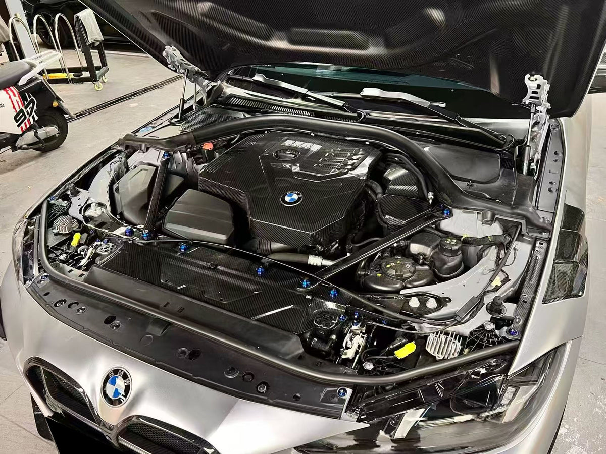 BMW 4 Series engine bay carbon fiber panels are shown in an angled view of a silver car under an open hood.