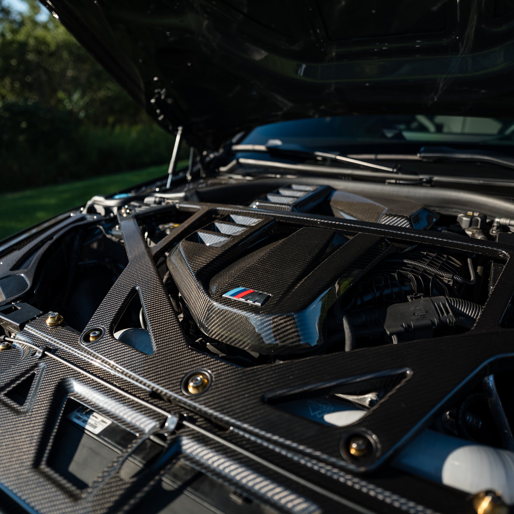 Close-up of the OEM style carbon fiber engine cover and CSL style strut brace on RAG's BMW G80 M3