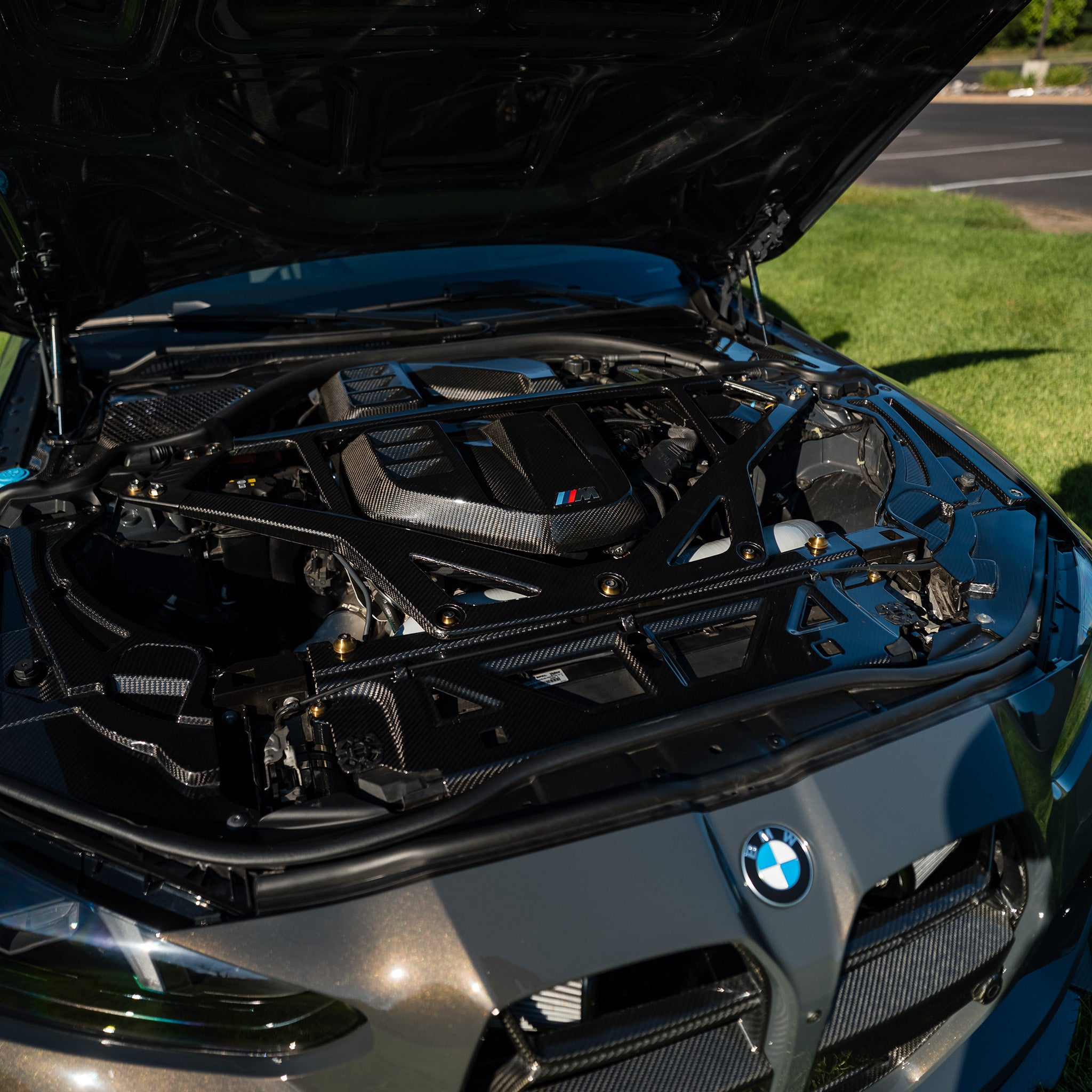 RAG Spec full carbon fiber engine bay kit installed on a BMW G80 M3, shown from a front three-quarter angle