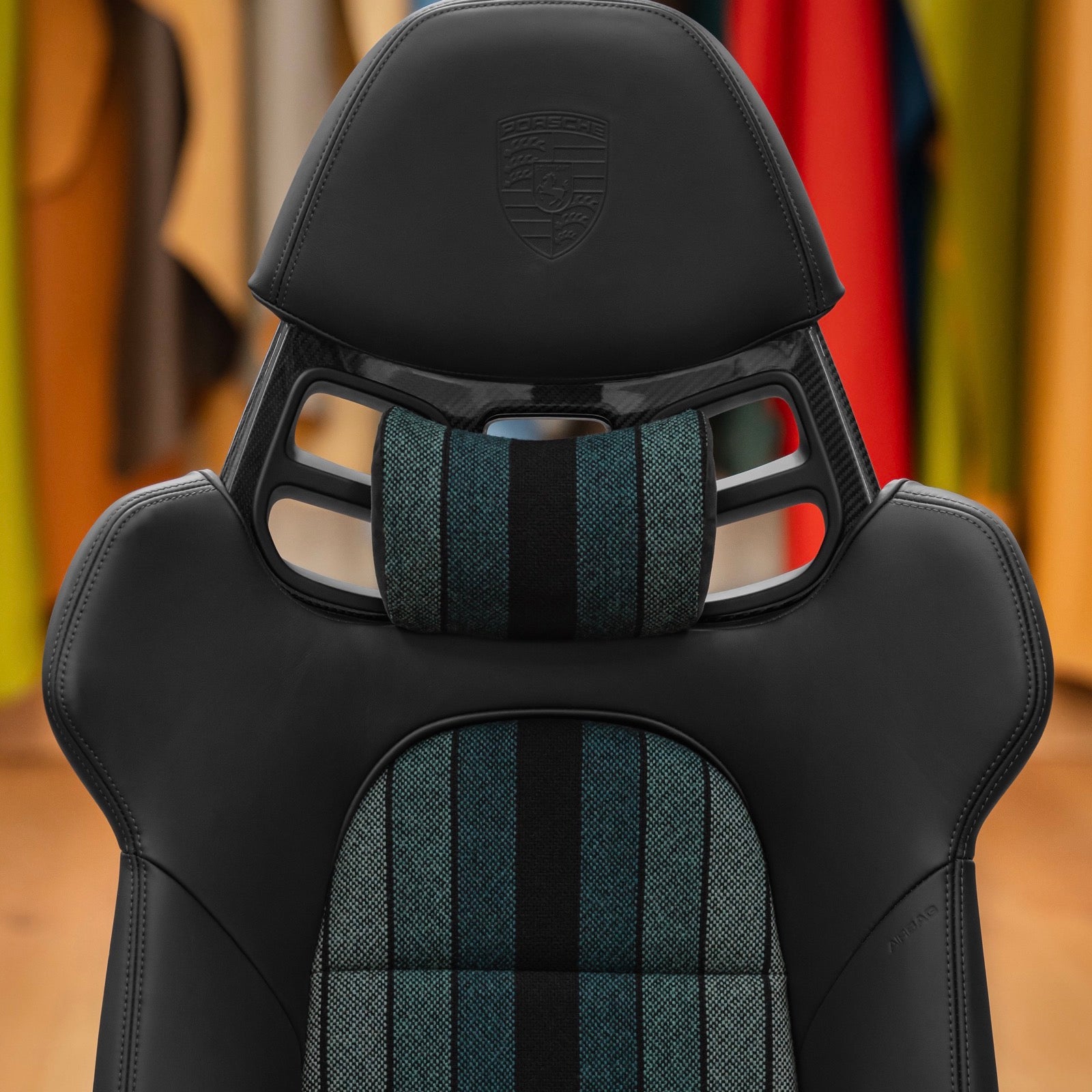 Green and black striped headrest pillow mounted in the headrest opening of a Porsche 918 style carbon full bucket seat