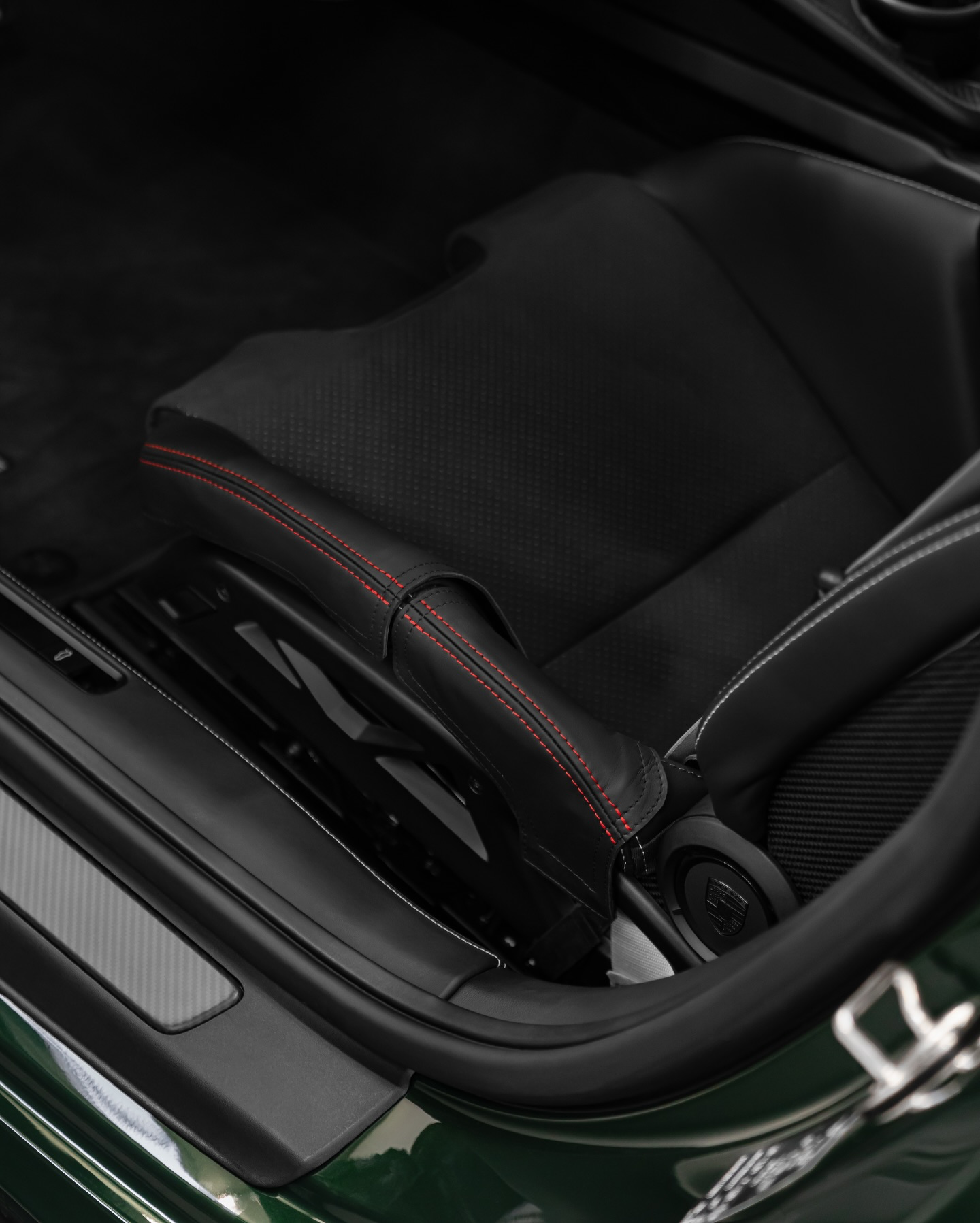 Porsche 992.2 folding bucket seat side bolster protector close up, black leather with red stitching