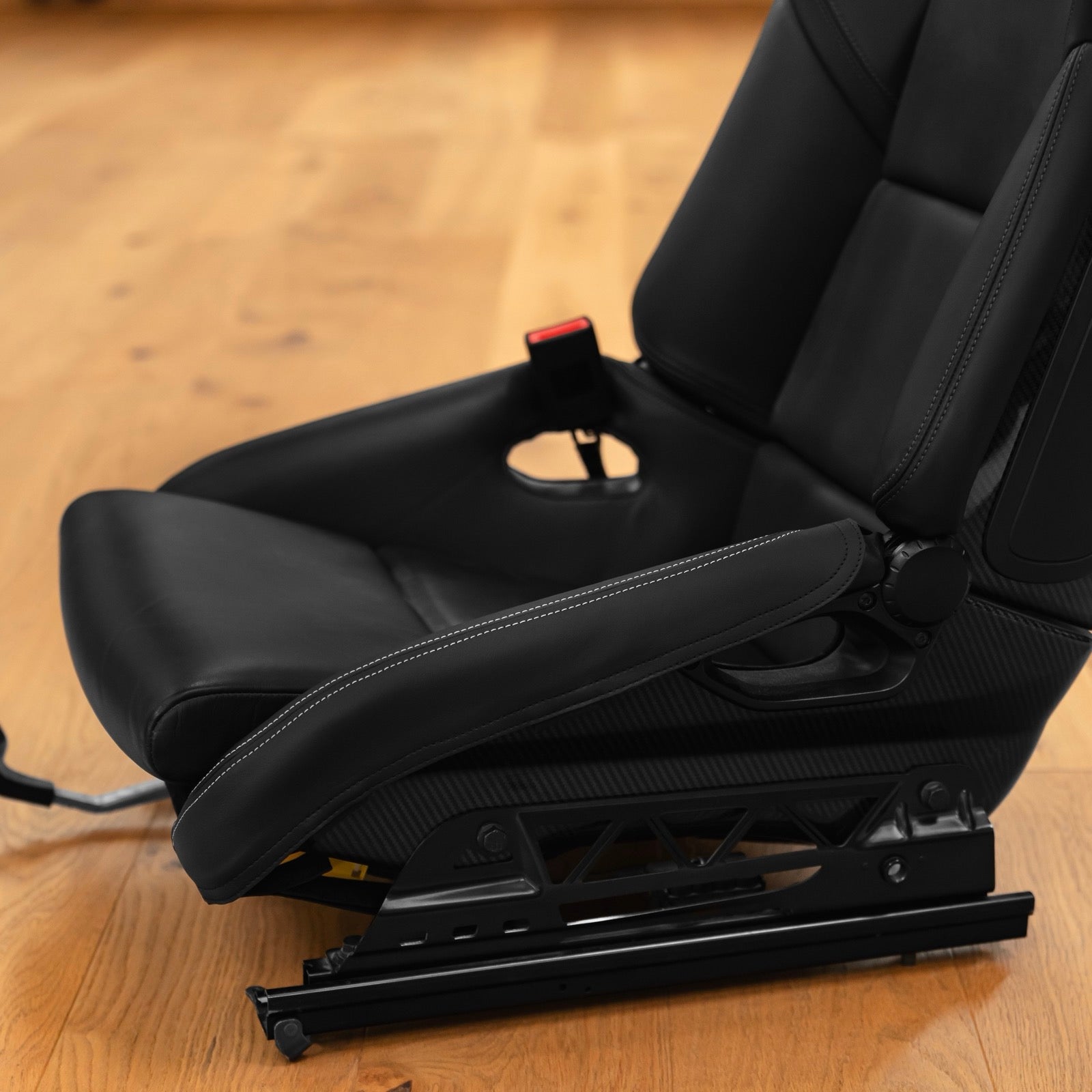 Porsche 997 folding carbon bucket seat with black leather bolster protector and white contrast stitching on the outer side bolster