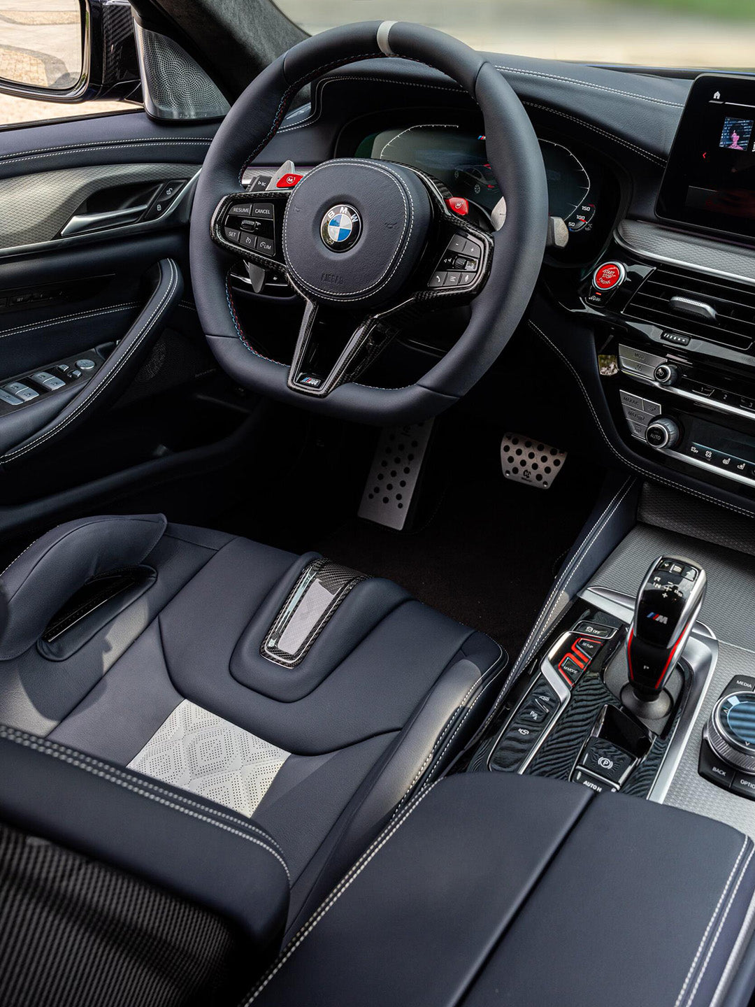 BMW M5 F90 cockpit with custom carbon fiber bucket seat, M steering wheel and white-on-navy quilted leather, aftermarket interior upgrade