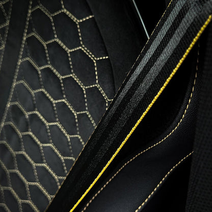 Audi RS bucket seat material detail – dark Alcantara honeycomb bolster meeting black Nappa leather with gold accent stitching edge