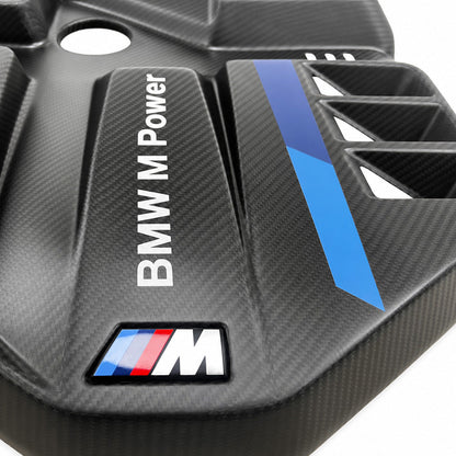 Detail of BMW G8X S58 EVE carbon fiber engine cover showing M tricolor strip and angular scoop vents