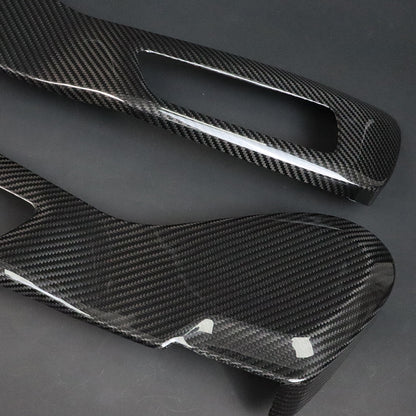 BMW G8X M2 M3 M4 Dry Carbon Side Seat Cover pair diagonal – both pieces showing outer carbon face with protective film, cutout visible on upper piece, dark grey background
