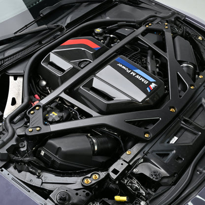 BMW G8X engine bay with black CSL style carbon fiber strut brace and Gold titanium bolts