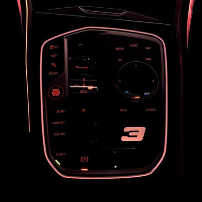 BMW M Illuminated Gear Selector Surround installed – warm pink rose LED glow with illuminated 3 Series badge in BMW G-series cabin