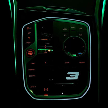 BMW M Illuminated Gear Selector Surround installed – bright green LED active matching door and console ambient strips in dark G-series interior