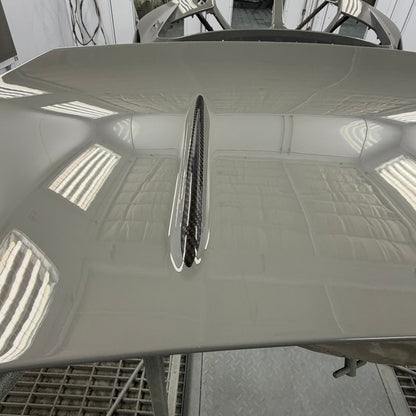 BMW G87 M2 CS carbon fiber trunk lid with the raised top character lines left in exposed carbon against painted body, a custom carbon accent finish