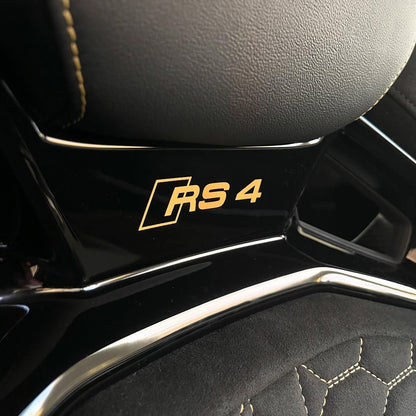 Audi RS4 bucket seat headrest area – gloss black backrest shell with gold RS4 badge close-up