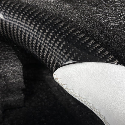 Close-up of the twill carbon fiber weave meeting the white leather grip with cross stitching