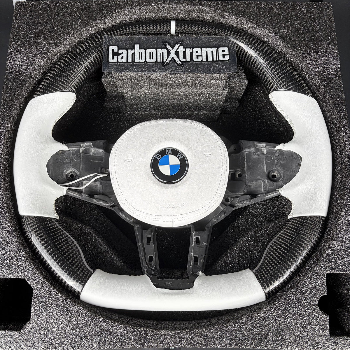 Custom carbon fiber steering wheel for BMW G80 M3, front view with white leather grip, flat top and bottom and white 12 o'clock stripe