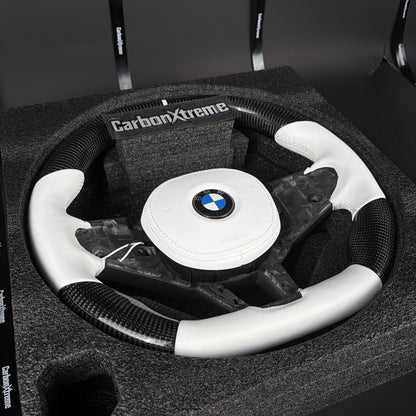Three-quarter view of the custom carbon fiber steering wheel showing the white leather flat bottom section