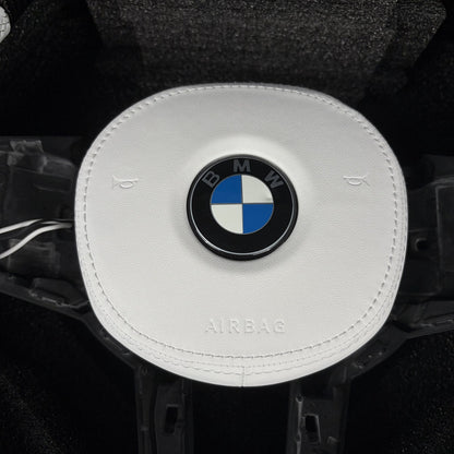 White leather airbag cover with stitched edges on the custom carbon fiber steering wheel