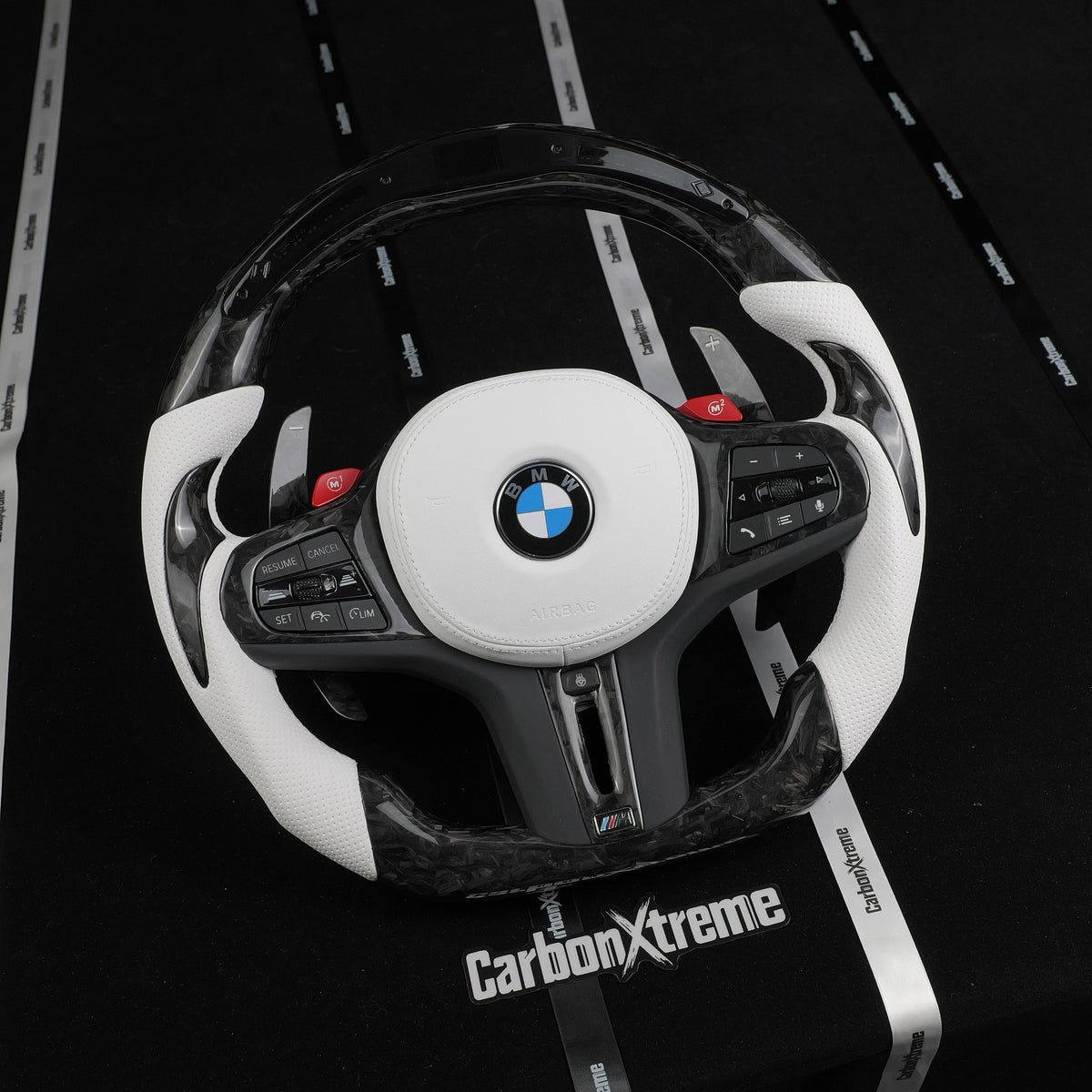 Angled front view of the custom forged carbon fiber LED steering wheel with white leather airbag cover