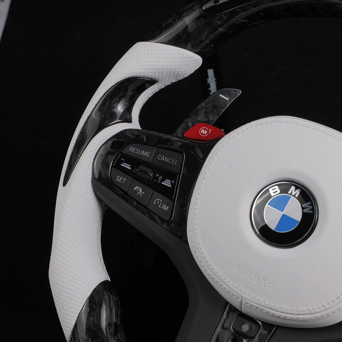 Left perforated leather grip with cruise control buttons and red M1 button on the custom forged carbon steering wheel