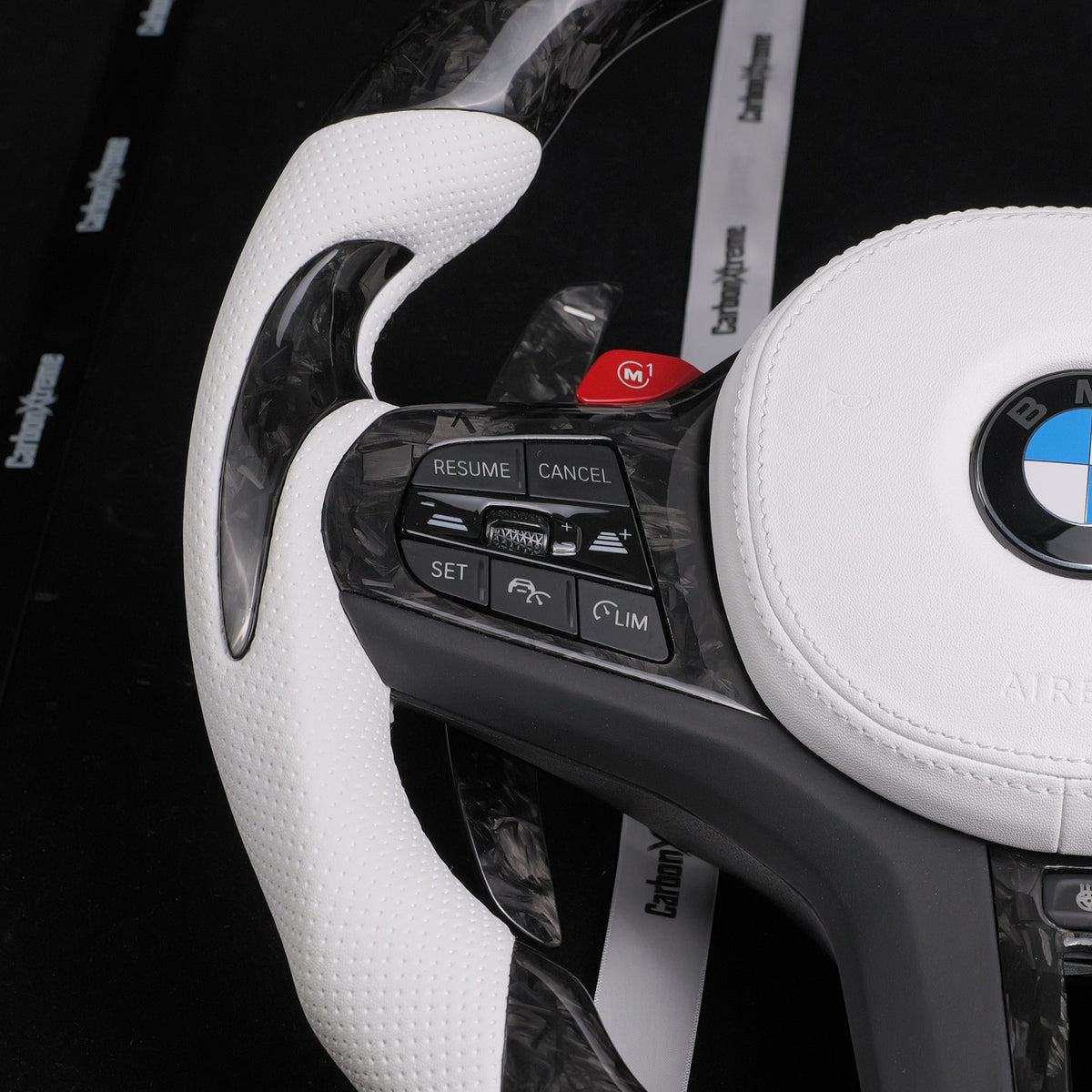 Side view of the white perforated leather grip and shift paddle on the custom forged carbon steering wheel