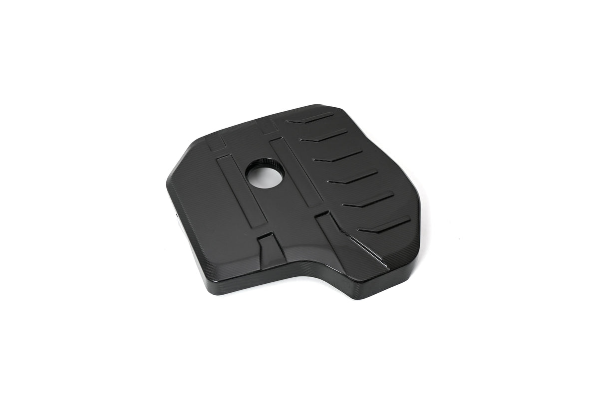 BMW G22 4 Series B48 carbon fiber engine cover is angled on white with a round oil opening and raised ribs.