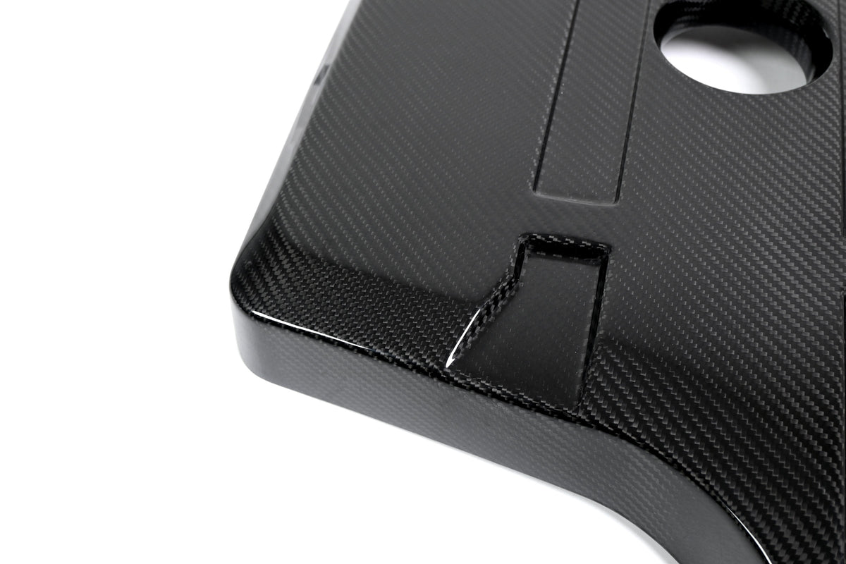 BMW G22 4 Series B48 carbon fiber engine cover is shown close up with its front recess and round oil opening.