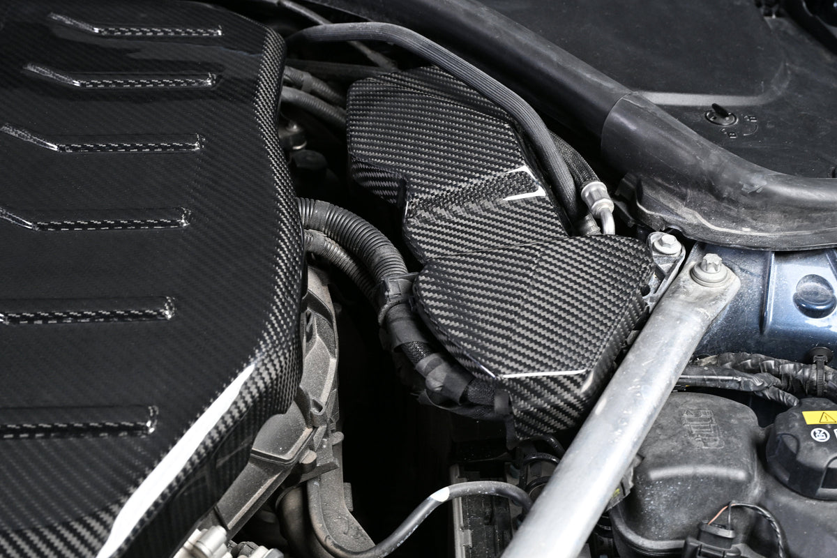 BMW G22 4 Series carbon fiber ECU battery terminal cover is shown installed beside the engine cover and hoses.