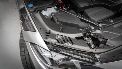 BMW G22 4 Series carbon fiber headlight cover panels are shown above a silver car's headlight with slots visible.