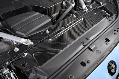 BMW G22 4 Series carbon fiber slam panel cover is shown installed across the front of a blue car at an angle.