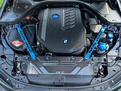 BMW G22 4 Series carbon fiber slam panel cover is shown from above at the front of an engine bay with blue bars.