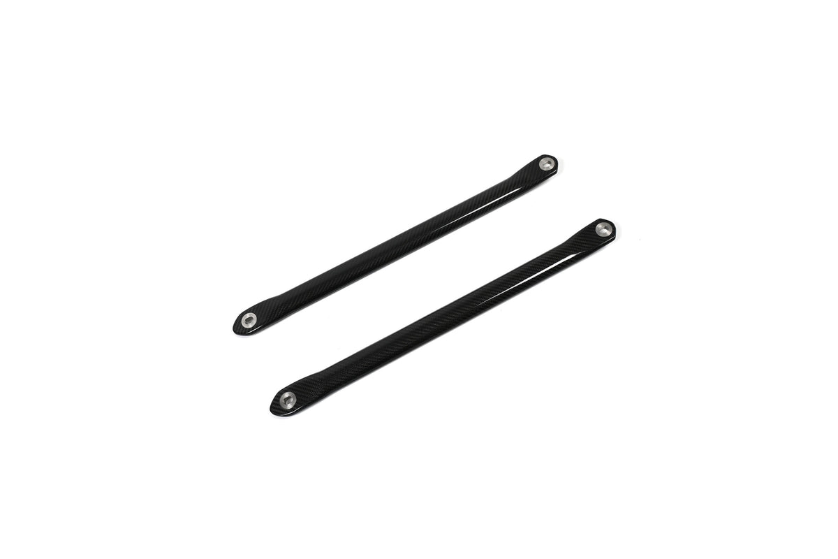 BMW G22 4 Series carbon fiber strut brace bars run diagonally upward to the right with metal end sleeves visible.