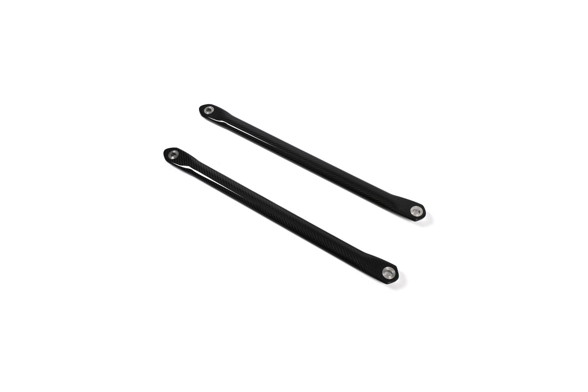 BMW G22 4 Series carbon fiber strut brace bars run diagonally downward to the right on a white background.