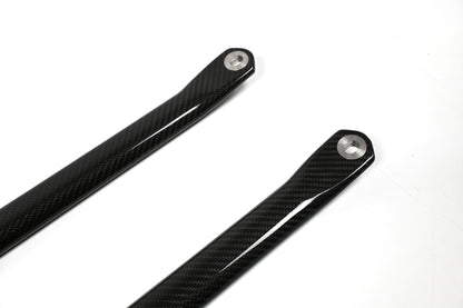 BMW G22 4 Series carbon fiber strut brace bars are shown close up with metal sleeves at the upper right ends.