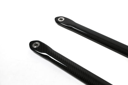 BMW G22 4 Series carbon fiber strut brace bars are seen close up with the left ends and round metal sleeves.