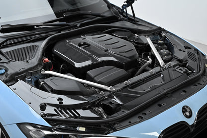 BMW 4 Series engine bay carbon fiber covers are fitted to a blue car, shown from an angled front view.