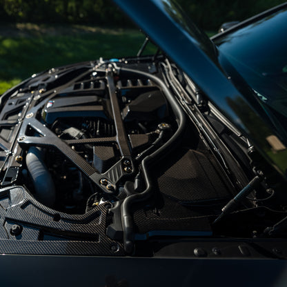 Side view of the carbon fiber cowl panel and black CSL style strut brace installed on a BMW G80 M3