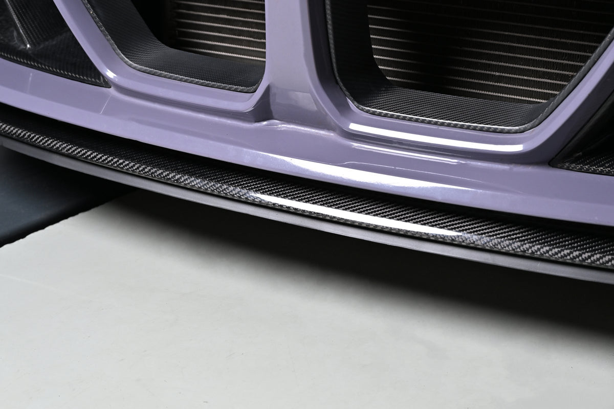 Close-up of the CSL style carbon fiber center lip under a BMW G82 M4 front bumper