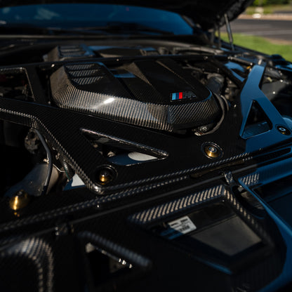 Close-up of the OEM style carbon fiber engine cover and CSL style strut brace installed on a BMW G80 M3