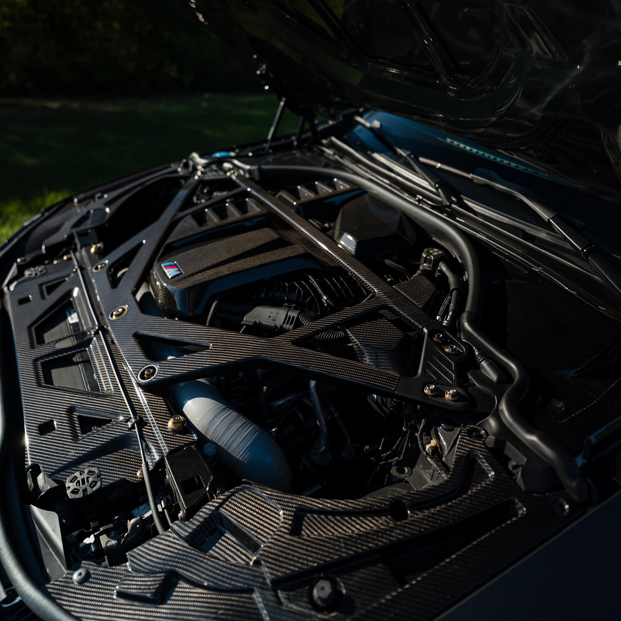 Wide view of the RAG Spec full carbon fiber engine bay kit installed on a BMW G80 M3
