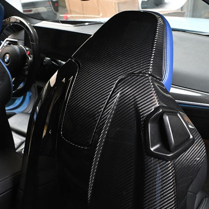 BMW G8X M2 M3 M4 Carbon Fiber Seat Back Replacement installed, full view of gloss carbon shell on front seat with blue bolsters and cabin background
