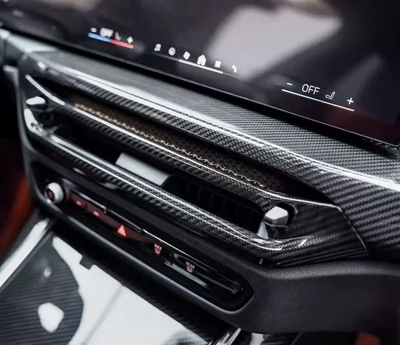 Carbon fiber center air vent trim installed below the curved display on a BMW M3 M4 LCI