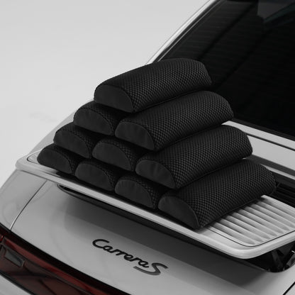 Eight Porsche carbon bucket seat lumbar support pillows stacked on the rear deck of a silver 911 Carrera S