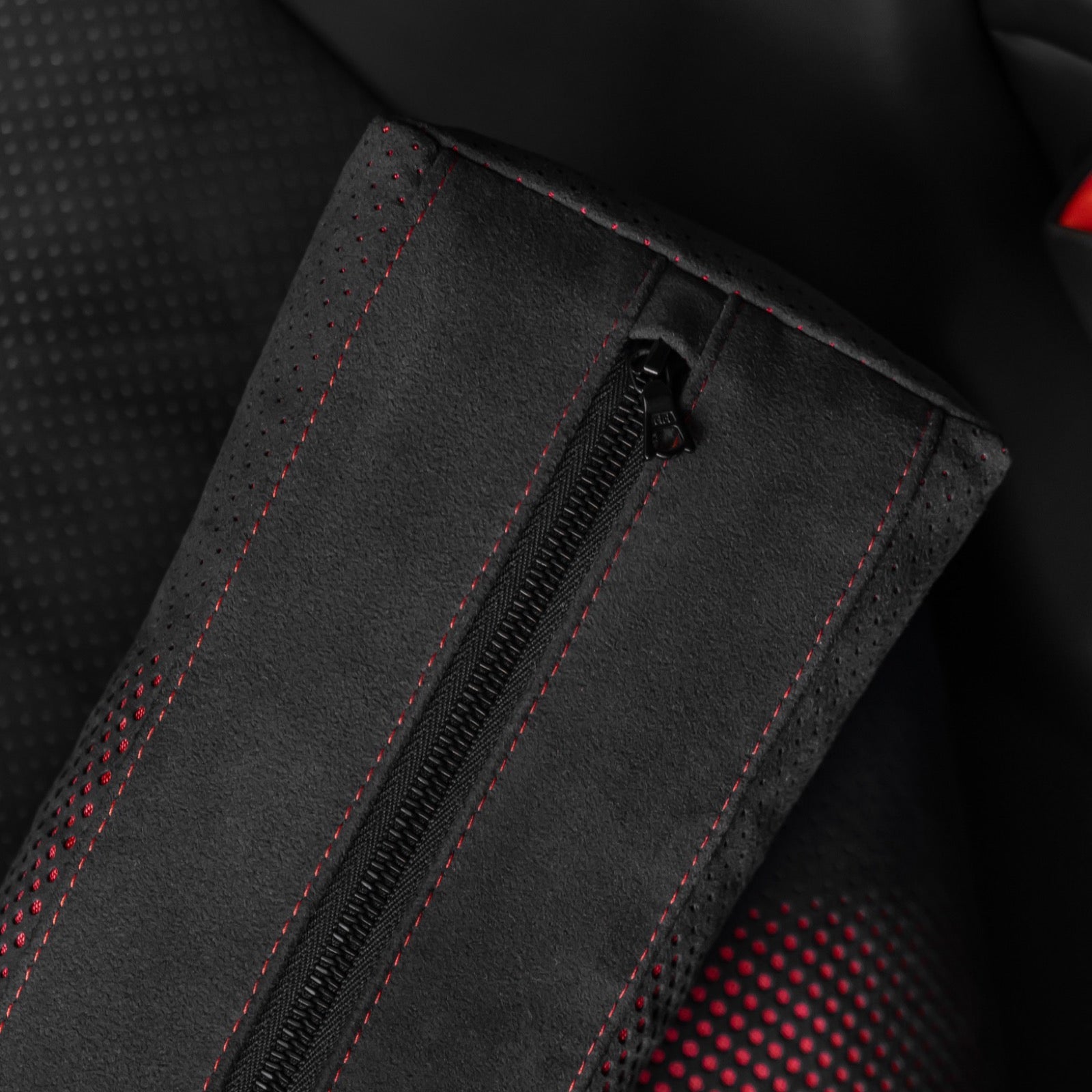 Close up detail of the zipper and red contrast stitching on a black Alcantara Porsche lumbar support pillow