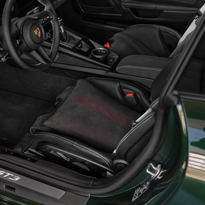 Black Alcantara space increase pillow with red perforated dot pattern installed in a Porsche 992.2 GT3 carbon folding bucket seat in a green 911